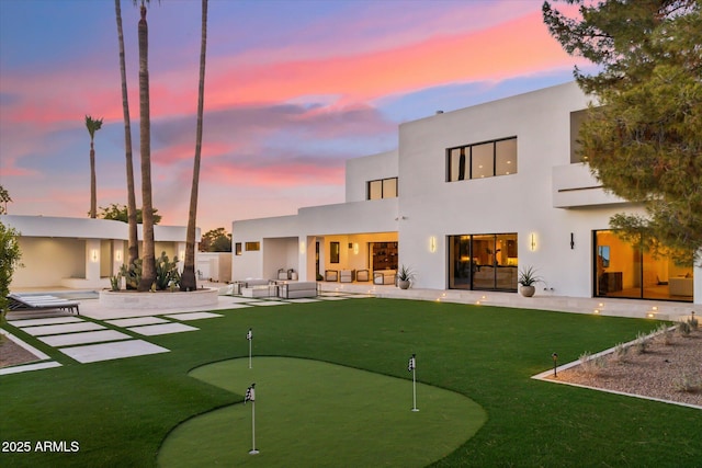 back house at dusk with a patio area and outdoor lounge area