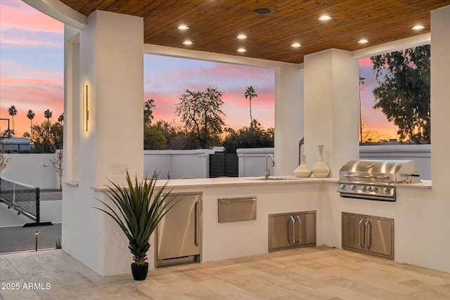 patio terrace at dusk featuring sink, a grill, and exterior kitchen