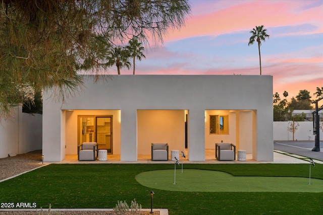 back house at dusk featuring a patio