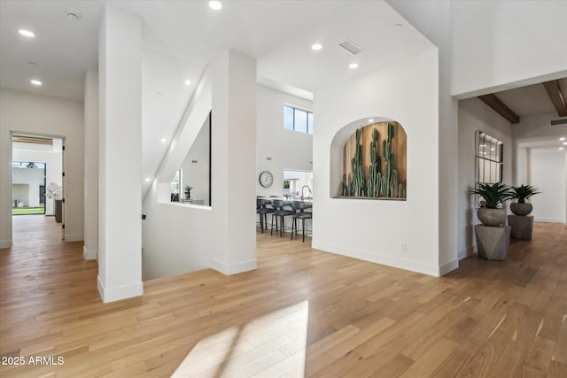 hall featuring light hardwood / wood-style flooring and a towering ceiling