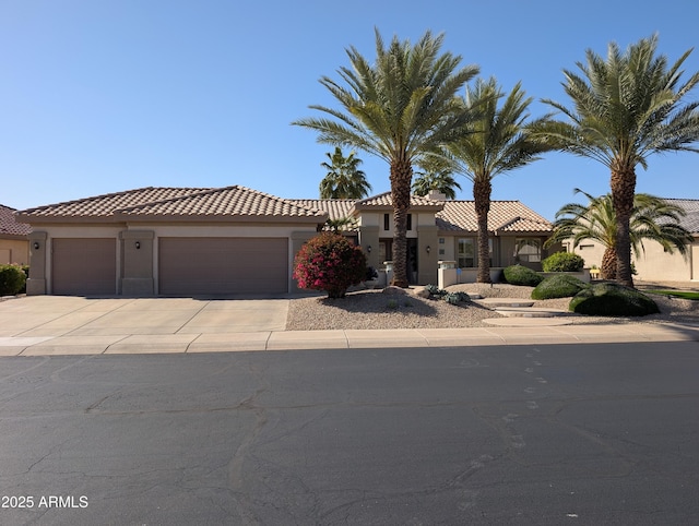 mediterranean / spanish-style house featuring stucco siding, driveway, an attached garage, and a tile roof