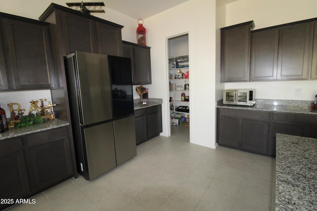 4923 W Weeping Willow Way, Laveen, AZ 85339 - kitchen with freestanding refrigerator, stone countertops, dark brown cabinets, and light tile patterned floors