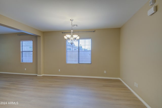 unfurnished room featuring a notable chandelier and light hardwood / wood-style floors