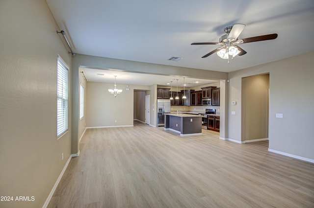 unfurnished living room featuring ceiling fan with notable chandelier and light wood-type flooring