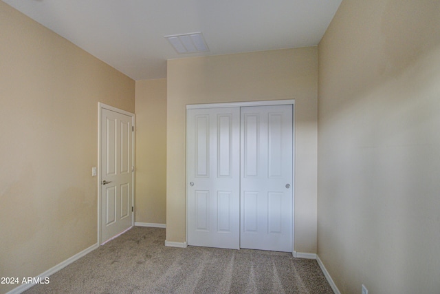 unfurnished bedroom with light carpet and a closet