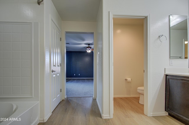 bathroom featuring a tub, ceiling fan, hardwood / wood-style floors, toilet, and vanity