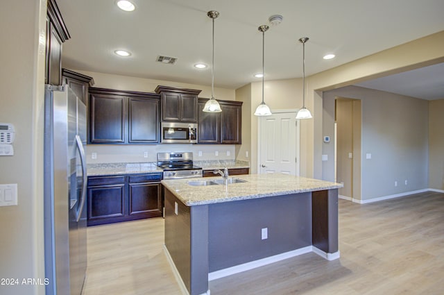 kitchen featuring light stone countertops, sink, light hardwood / wood-style floors, a kitchen island with sink, and appliances with stainless steel finishes