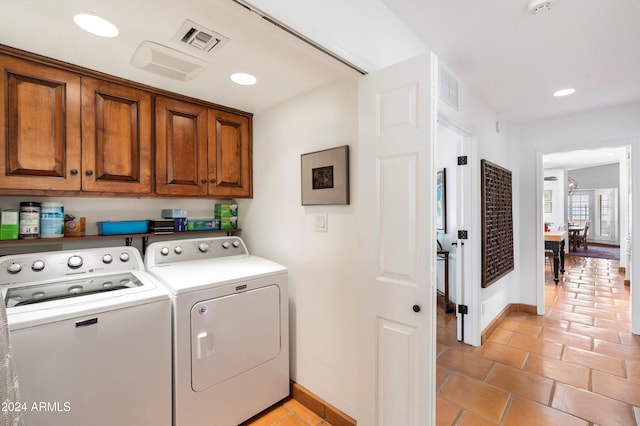 clothes washing area featuring washer and clothes dryer, light tile patterned floors, and cabinets