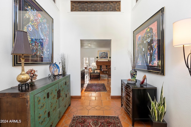 hallway with a high ceiling and light tile patterned floors