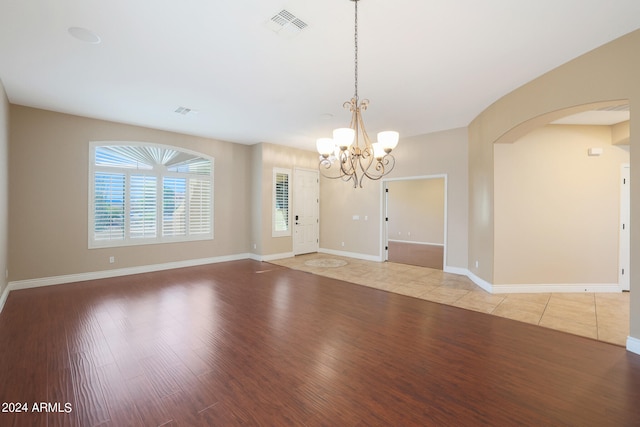 unfurnished room featuring an inviting chandelier and light wood-type flooring