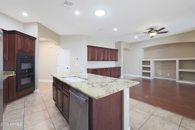 kitchen featuring light hardwood / wood-style flooring, a center island with sink, black double oven, ceiling fan, and stainless steel dishwasher