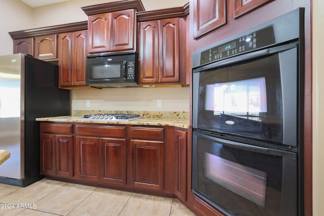 kitchen featuring light stone counters, light tile patterned floors, and black appliances