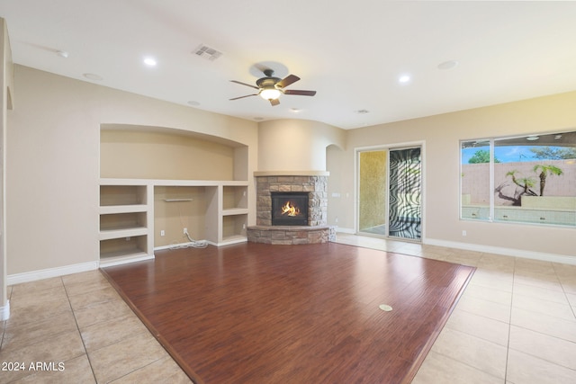 unfurnished living room featuring a fireplace, ceiling fan, light hardwood / wood-style flooring, and built in shelves