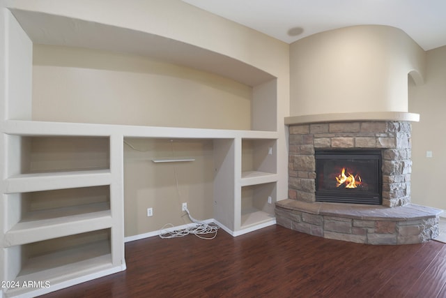 unfurnished living room featuring a fireplace, dark wood-type flooring, and built in features