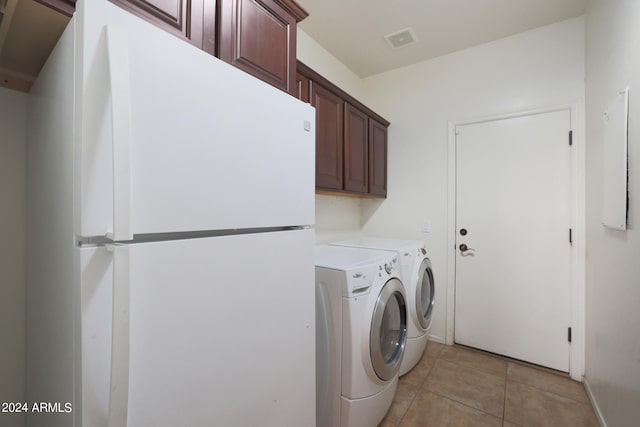 laundry room with light tile patterned floors, washing machine and clothes dryer, and cabinets