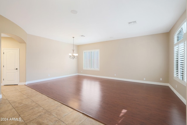 unfurnished room featuring a chandelier and light hardwood / wood-style floors