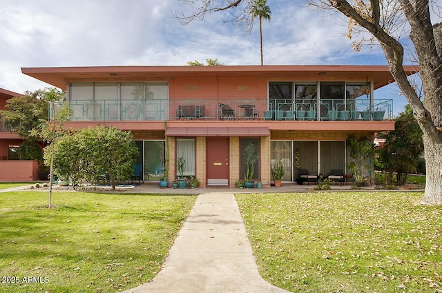 view of front of property featuring a front yard and a balcony