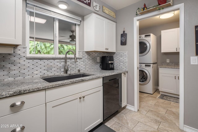 kitchen featuring light stone counters, stacked washer and dryer, a sink, white cabinets, and decorative backsplash