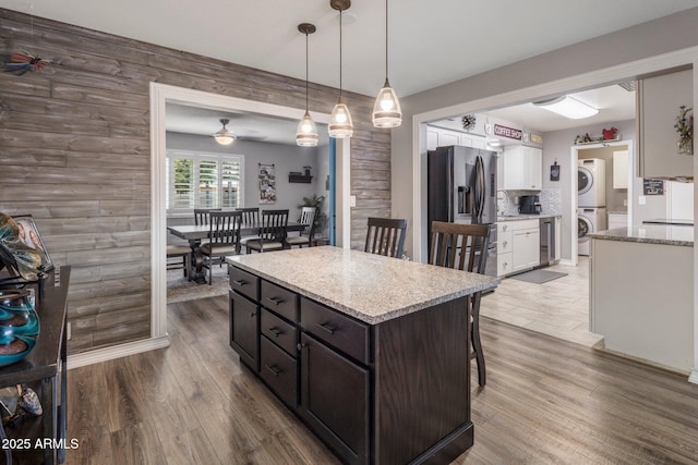 kitchen with stacked washer / dryer, white cabinetry, dark brown cabinets, stainless steel refrigerator with ice dispenser, and decorative light fixtures