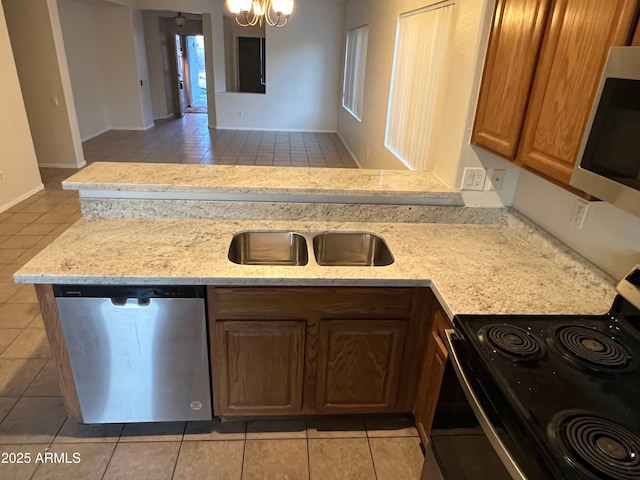 kitchen featuring sink, a chandelier, light tile patterned floors, light stone counters, and stainless steel appliances