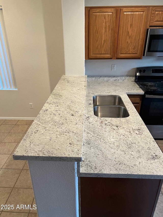 kitchen with light stone counters, sink, light tile patterned floors, and appliances with stainless steel finishes