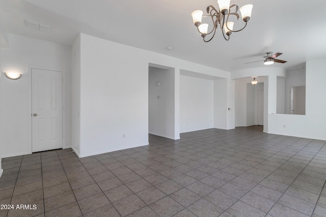 tiled spare room featuring ceiling fan with notable chandelier