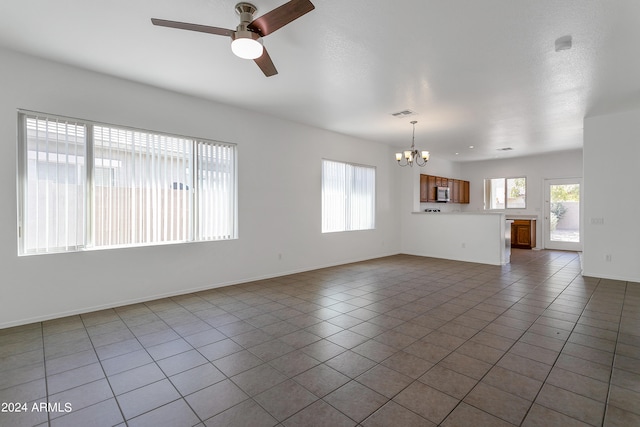 unfurnished living room with tile patterned floors and ceiling fan with notable chandelier