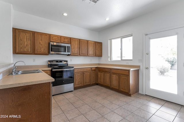 kitchen with stainless steel appliances, sink, and light tile patterned floors