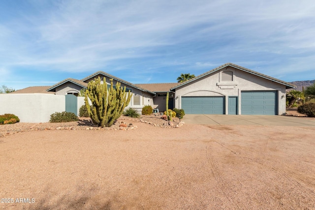 view of front facade featuring driveway, fence, an attached garage, and stucco siding