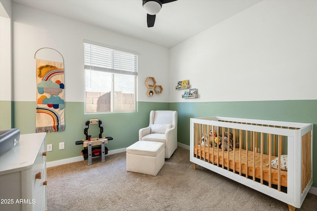 carpeted bedroom featuring ceiling fan and a nursery area