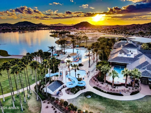 aerial view at dusk featuring a water and mountain view