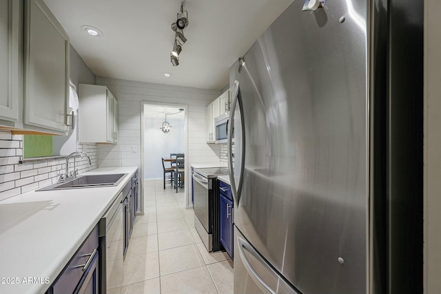 kitchen with sink, light tile patterned floors, blue cabinetry, appliances with stainless steel finishes, and white cabinetry