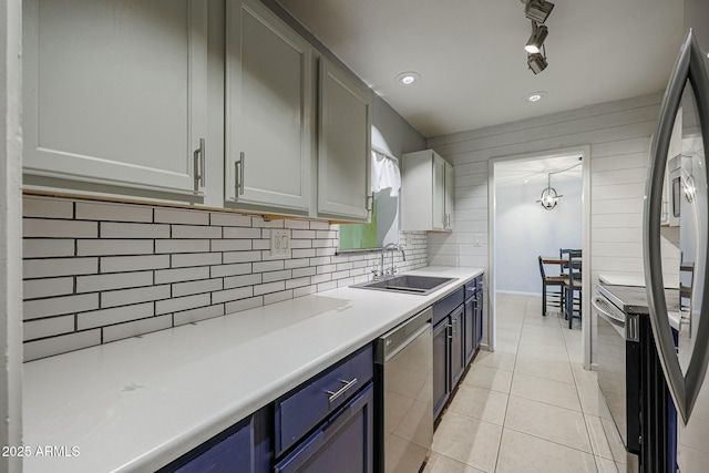 kitchen featuring backsplash, sink, blue cabinetry, light tile patterned flooring, and stainless steel appliances