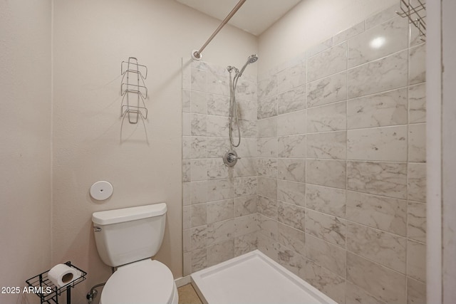 bathroom with a tile shower and toilet