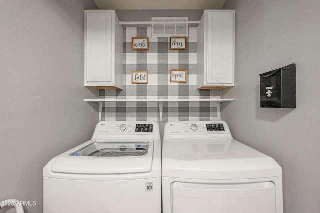 clothes washing area featuring washer and dryer and cabinets