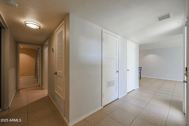 corridor featuring light tile patterned floors and a textured ceiling