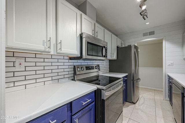 kitchen featuring blue cabinetry, rail lighting, stainless steel appliances, white cabinets, and light tile patterned flooring