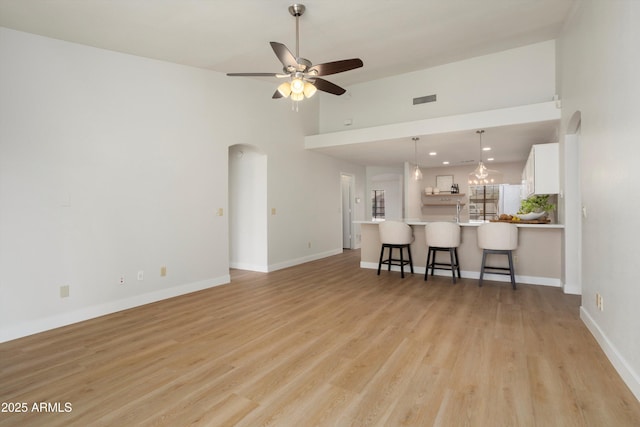 6366 W Saint John Ave, Glendale, AZ 85308 - living room with arched walkways, high vaulted ceiling, ceiling fan, light wood finished floors, and baseboards