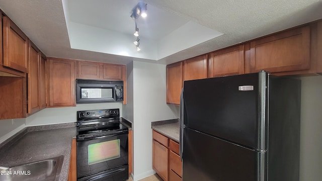 kitchen featuring track lighting, a textured ceiling, a raised ceiling, and black appliances