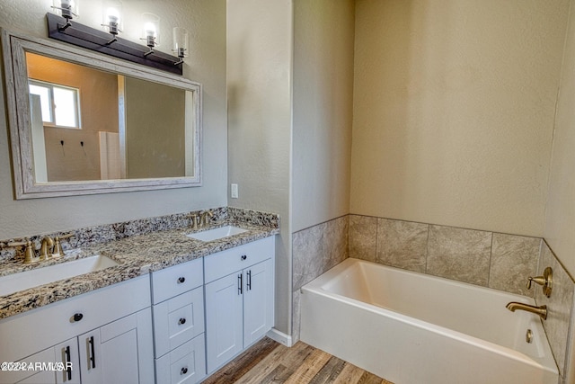 bathroom with hardwood / wood-style flooring, vanity, and a bathing tub