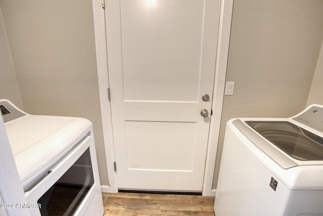 clothes washing area with light hardwood / wood-style floors and washer and dryer