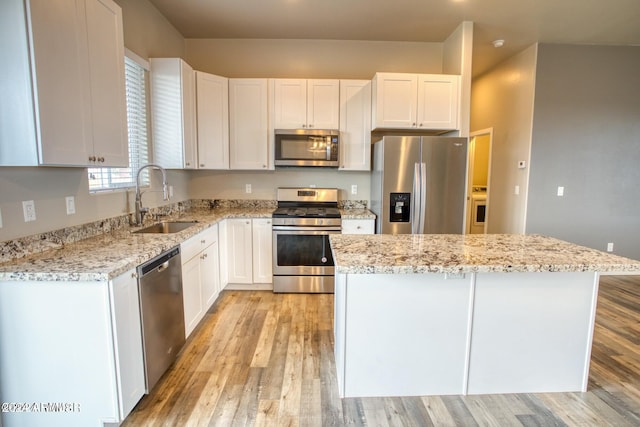 kitchen featuring sink, a kitchen island, light hardwood / wood-style flooring, white cabinetry, and stainless steel appliances