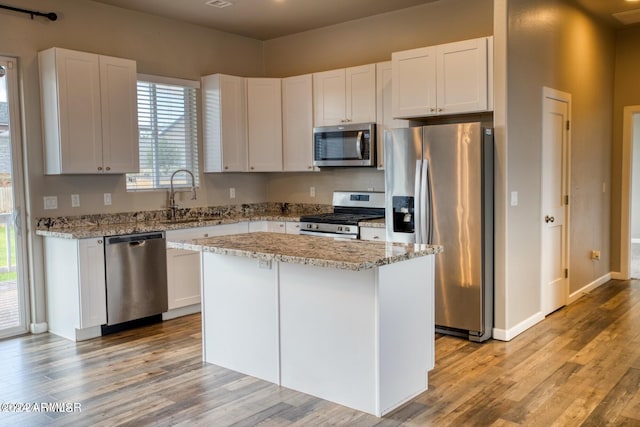 1028 W Ione Ln, Taylor, AZ 85939 - kitchen featuring stainless steel appliances, a center island, a sink, light wood finished floors, and white cabinets