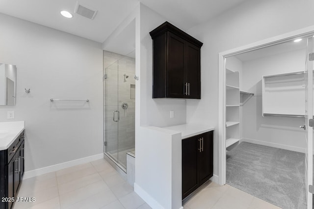 1301 W Via De Olivos, Queen Creek, AZ 85140 - bathroom featuring vanity, a shower stall, baseboards, a walk in closet, and tile patterned floors