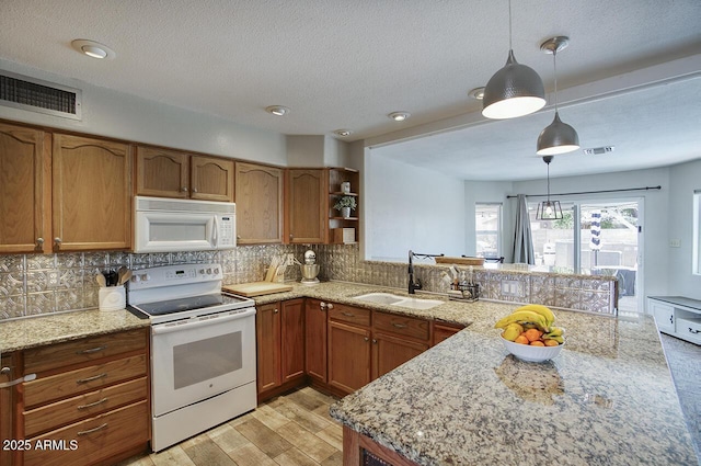 3203 W Libby St, Phoenix, AZ 85053 - kitchen featuring white appliances, a peninsula, tasteful backsplash, brown cabinets, and a textured ceiling
