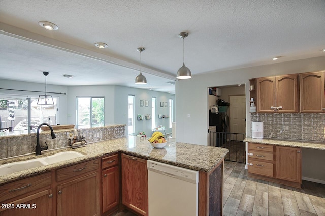 3203 W Libby St, Phoenix, AZ 85053 - kitchen featuring dishwasher, backsplash, brown cabinetry, pendant lighting, and a textured ceiling