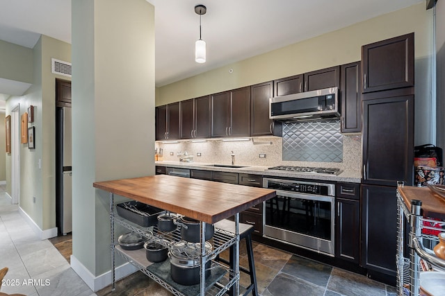 kitchen with sink, backsplash, hanging light fixtures, dark brown cabinets, and stainless steel appliances