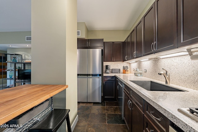 kitchen featuring stainless steel refrigerator, sink, wooden counters, backsplash, and dark brown cabinets