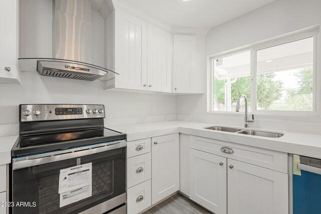 kitchen with appliances with stainless steel finishes, white cabinets, light hardwood / wood-style flooring, exhaust hood, and sink