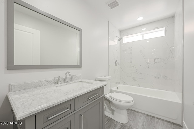 full bathroom with toilet, vanity, and tiled shower / bath